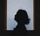 a silhouette of a person looking out of a window